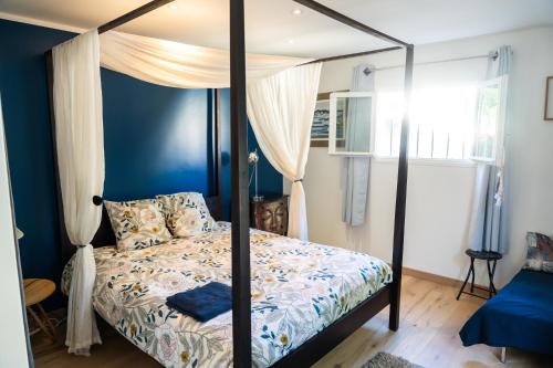 a bedroom with a four poster bed with blue walls at Villa Bellavista in Marsanne