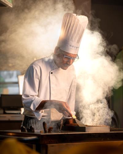 a chef preparing food on top of a grill at Novotel Kolkata Hotel and Residences in Kolkata