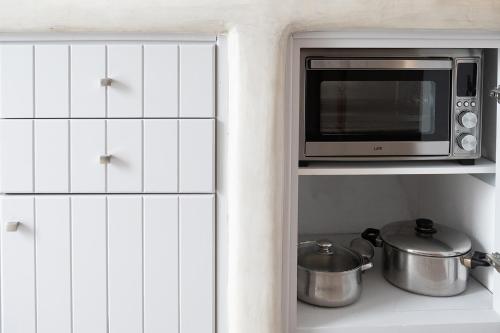 a kitchen with a microwave and some pots and pans at The Wine Nest in Megalokhori