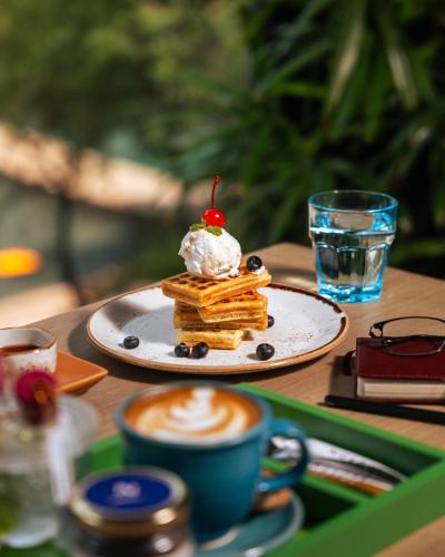 a plate of pancakes with whipped cream and a cup of coffee at Novotel Kolkata Hotel and Residences in Kolkata