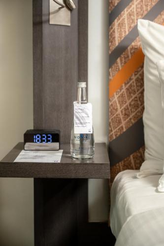 a bottle of water sitting on a table next to a bed at Novotel Kolkata Hotel and Residences in Kolkata