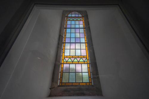 a stained glass window in a white wall at St Michaels Lodge in Richmond