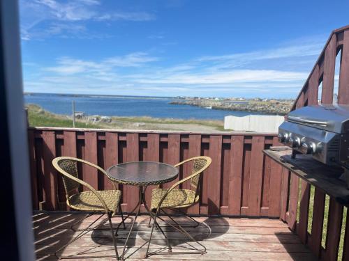 a table and chairs on a balcony with a grill at Robbins by the Sea in Bonavista