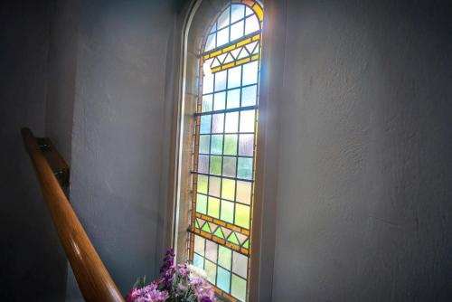 a stained glass window in a stair case with flowers at St Michaels Lodge in Richmond