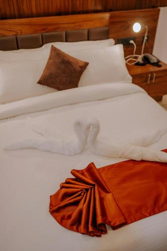 a large white bed with a orange dress on it at refresh inn suits and rooms in Tāzhekkod