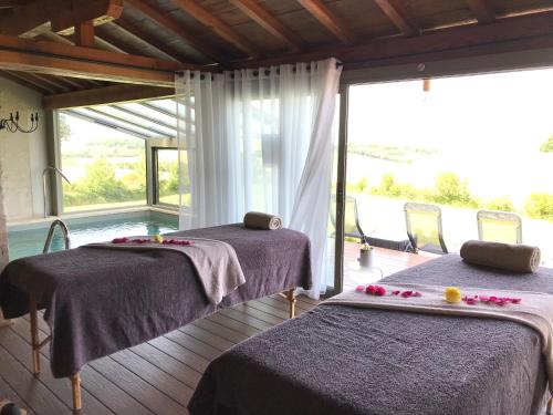 deux lits dans une chambre avec une grande fenêtre dans l'établissement Domaine Léa Chanflaur - Spa - La maison du bonheur, à Terraube