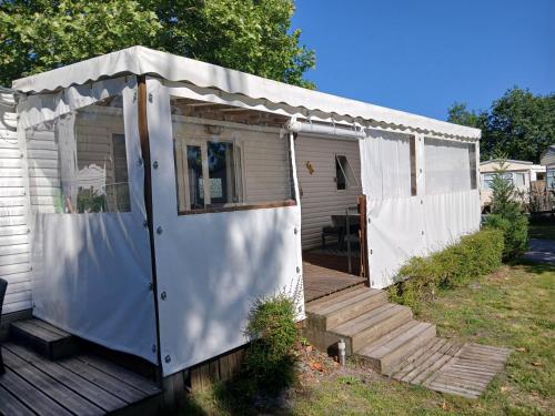 un hangar blanc avec une terrasse couverte et une terrasse dans l'établissement Mobil-home 415 camping la lande, à Mimizan