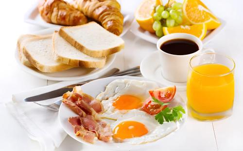 a table with plates of breakfast foods and a glass of orange juice at Aurum Heights Gateway Prestige Luxury Apartments - Gulberg Lahore in Lahore