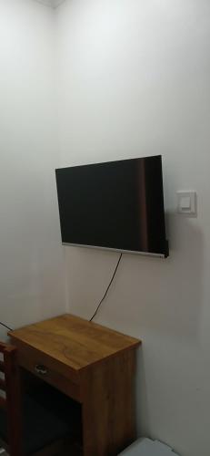 a flat screen tv on a wall with a wooden table at annies inn homestay in Cochin
