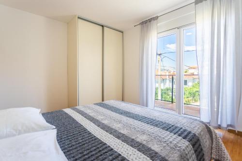 a bedroom with a bed and a large window at Apartman Nikša in Podstrana