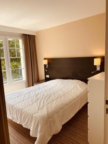 une chambre avec un grand lit et une grande fenêtre dans l'établissement Opale Sun Hardelot, à Neufchâtel-Hardelot