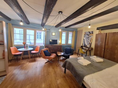 a room with a bed and chairs and a table at Maison Cliquot - Appartements Colmar Centre in Colmar