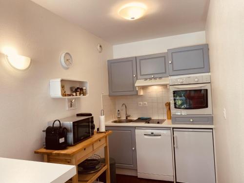 a small kitchen with white cabinets and a microwave at Opale Sun Hardelot in Neufchâtel-Hardelot