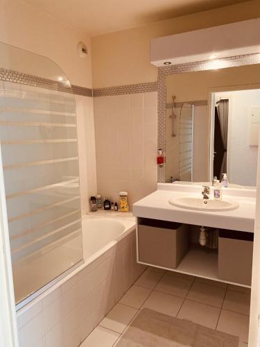 une salle de bain avec un lavabo, une baignoire et un miroir dans l'établissement Opale Sun Hardelot, à Neufchâtel-Hardelot