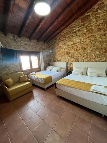 a bedroom with two beds and a stone wall at Villa con piscina, campo fútbol y pádel in Mas dʼen Rieres
