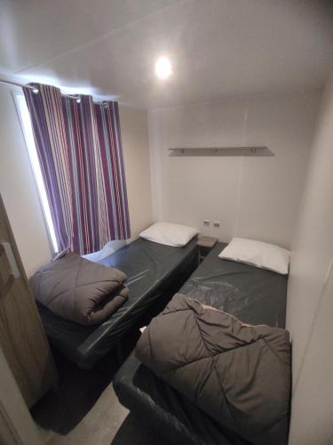 une petite chambre avec deux lits et une fenêtre dans l'établissement Sol à gogo 3 Chambres à 50 m de la plage, à Saint-Hilaire-de-Riez