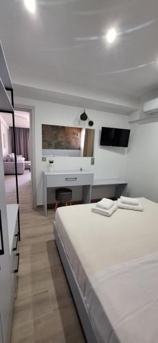 a white bedroom with a bed and a desk at Otium Studios in Limenaria