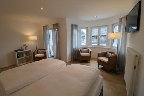 a bedroom with a large white bed and chairs at Landhotel Adler in Sigmarszell