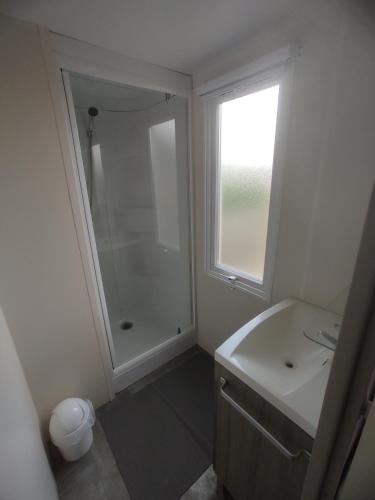 une salle de bain blanche avec une douche et un lavabo dans l'établissement Sol à gogo 3 Chambres à 50 m de la plage, à Saint-Hilaire-de-Riez