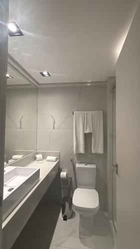 a bathroom with a toilet and a sink and a mirror at Flat TOP - No Praia Brava Hotel na ilha a beira mar in Florianópolis