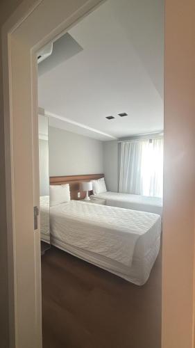a hotel room with two beds and a window at Flat TOP - No Praia Brava Hotel na ilha a beira mar in Florianópolis
