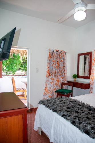 a bedroom with a bed and a desk and a television at Hotel Restaurant Wuarao - Antiguo Club Rolling Stones in Boca Chica