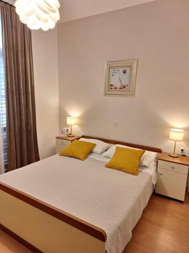 a bedroom with a large bed with two yellow pillows at Apartments Gržanov in Sutomišćica