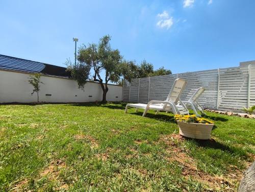 two lawn chairs and a basket of flowers in a yard at Casa Vacanza Kalispera in Alliste