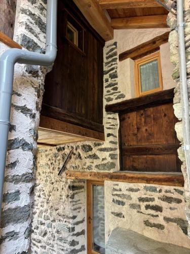 a house with a wooden door and a stone wall at Riverside room Pierre in Pontboset