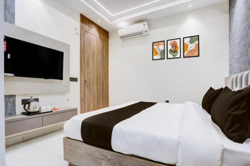 a bedroom with a large bed and a flat screen tv at HOTEL O SUKUN VILLA in New Delhi