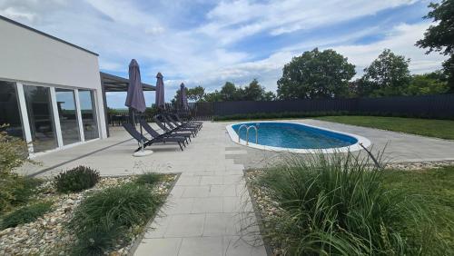 a pool with chairs and umbrellas in a yard at Casa Cordis in Korduševci