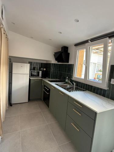 une cuisine avec des armoires vertes et un réfrigérateur blanc dans l'établissement Plain-pied lumineux & terrasse, à Mireval