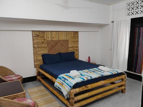 a bedroom with a bed with a wooden headboard at Globetrotters homestay in Jorhāt