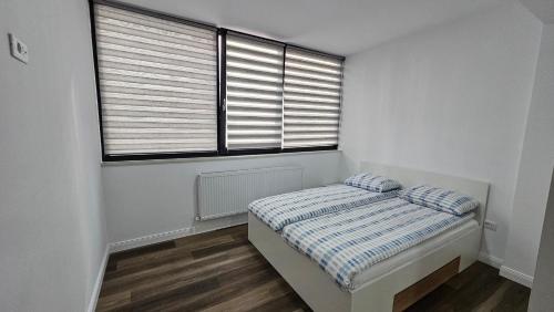 a small bedroom with a bed and two windows at Nordic Residence 5 in Suceava