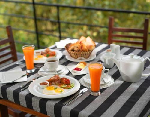 a table with plates of breakfast food and orange juice at Victoria Range Holiday Villas in Kandy
