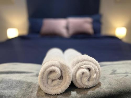 a pile of rolled towels on a bed at Cosy 3 Bedroom Apartment Near The O2 in London