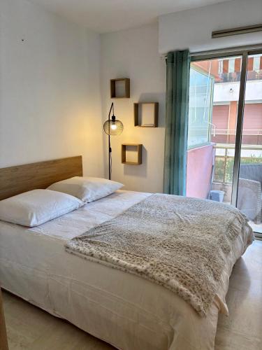 une chambre avec un grand lit et une grande fenêtre dans l'établissement Appartement proche de la plage et du centre ville, à Sainte-Maxime
