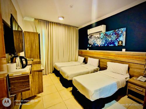 a hotel room with two beds and a television at Hotel Chatha Manoura- in Medina