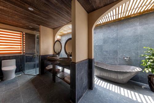 a bathroom with a tub and a sink and a mirror at Scenic Mountain Ecolodge Ninh Binh in Ninh Binh