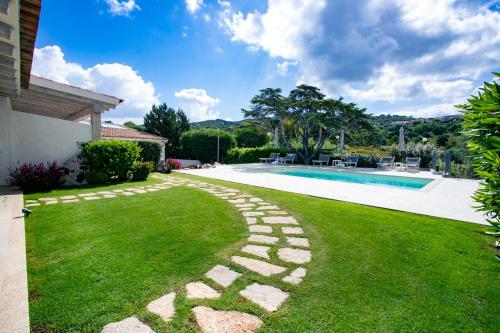 a backyard with a swimming pool and a green lawn at La Corte Di Pulicinu in Baja Sardinia