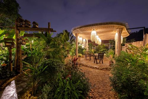 a garden with a pergola and a table and chairs at Scenic Mountain Ecolodge Ninh Binh in Ninh Binh