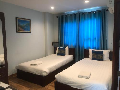 two beds in a room with blue curtains at T N A Hotel in Vang Vieng
