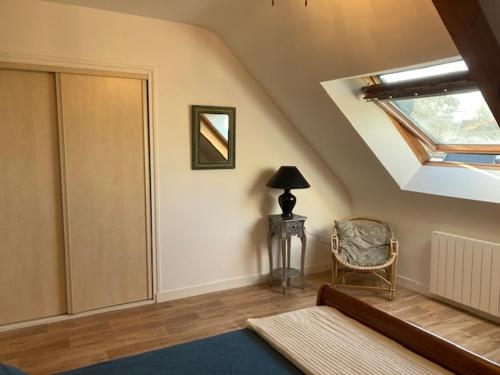 a attic room with a skylight and a chair and a window at Terre d'ajoncs in Saint-Philibert