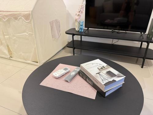 a table with a book and a remote control at Shelisa's Modern 3BR House at Suria Garden Puchong in Puchong