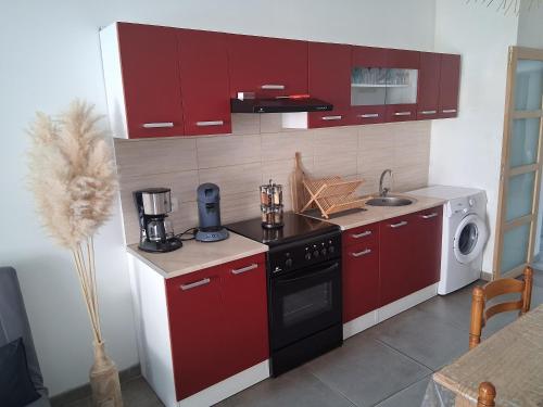 La cuisine est équipée de placards rouges et d'un four avec plaques de cuisson. dans l'établissement Logement à la Campagne! Entièrement indépendant, à Bonneuil-les-Eaux