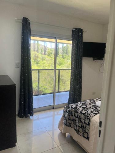 a bedroom with a bed and a large window at Cabañas del Fuego in Potrero de los Funes