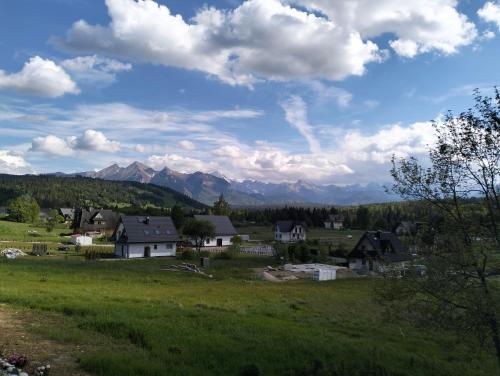 a village in a field with mountains in the background at Siedem Światów in Jurgów