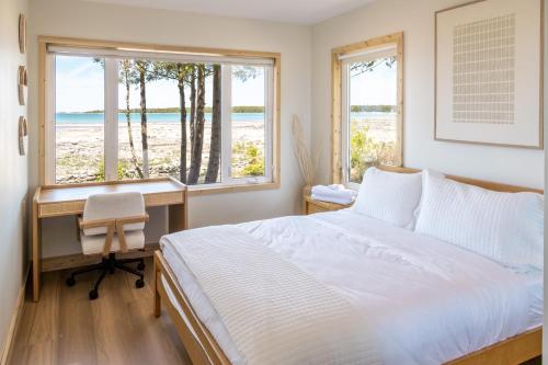 a bedroom with a bed and a desk and two windows at 300ft Modern Luxury Lakefront Hot Tub Steam Bath in Miller Lake
