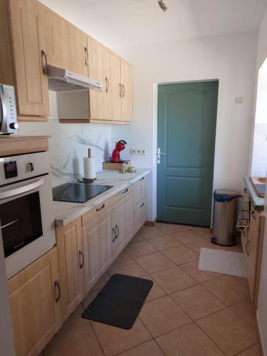 une cuisine avec des placards en bois et une porte bleue dans l'établissement Maison campagne proche Disney au calme, à Saint-Cyr-sur-Morin