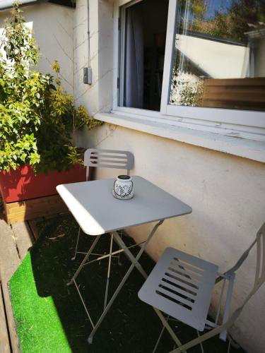 une table blanche et une chaise à côté d'une fenêtre dans l'établissement T1 Calme Séjour Pro et Détente, à Aurillac